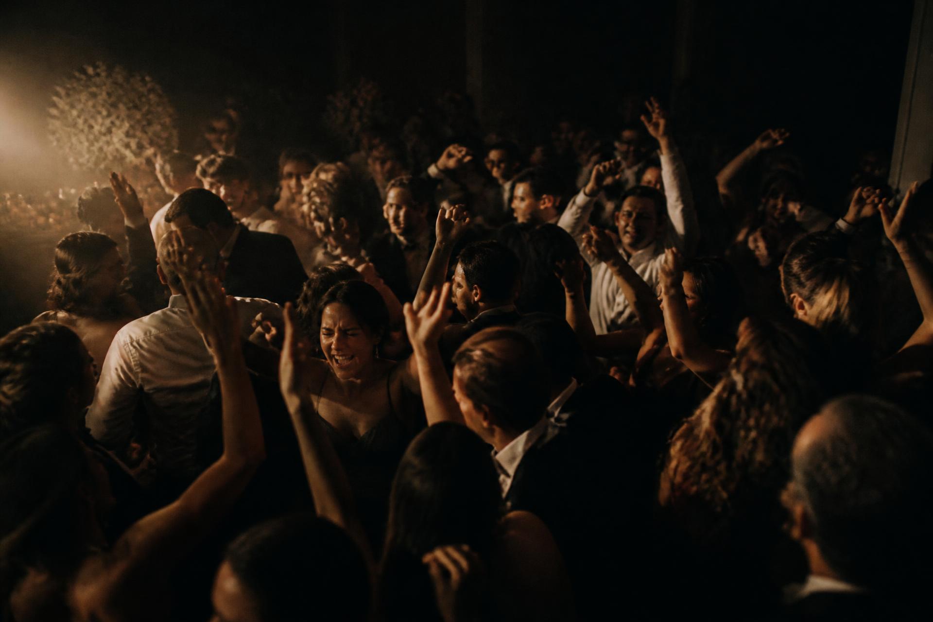 A packed wedding dance floor in Orlando, hands in the air, warm light overhead